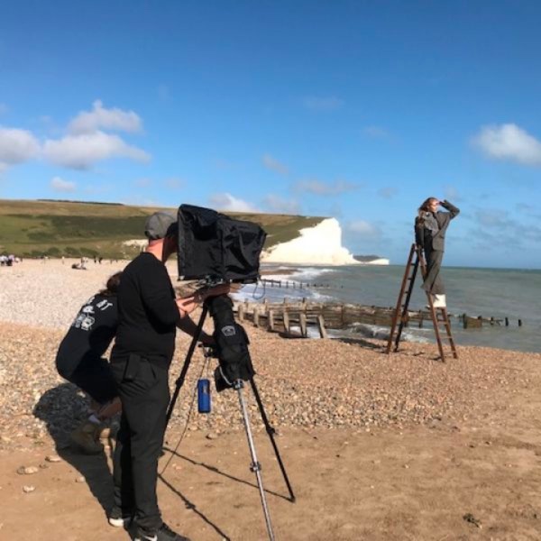 Picture of filming of person standing on a ladder at the beach